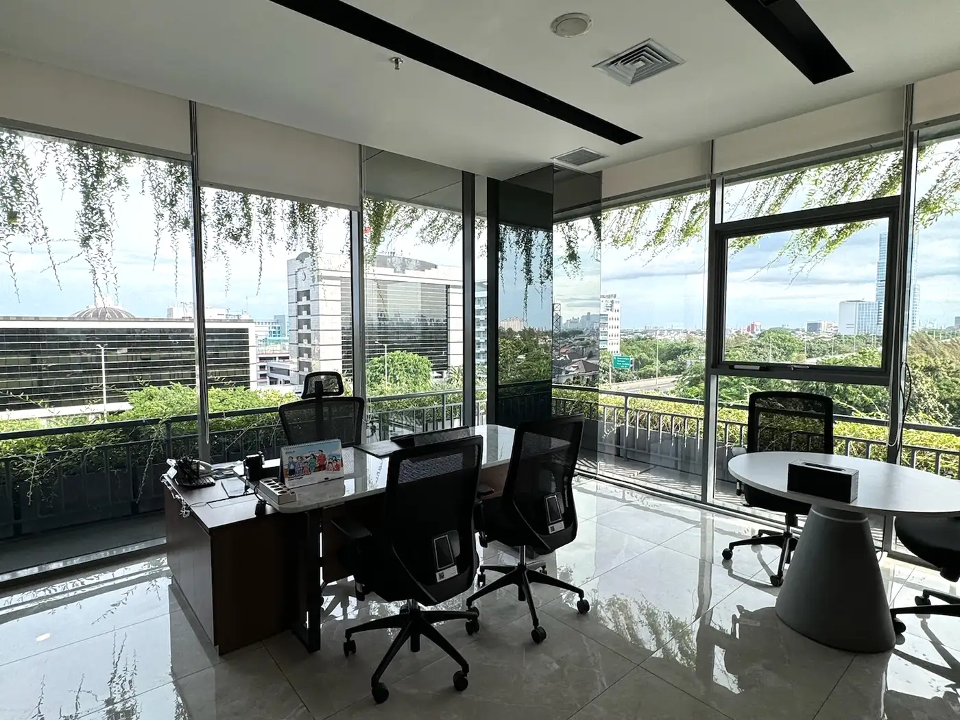 Ruang kantor di sudut gedung Jakarta dengan film pada dua dinding kaca dan meja kerja menempel ke kaca